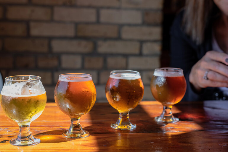 Four glasses of different craft beers lined up on a wooden table in a bar