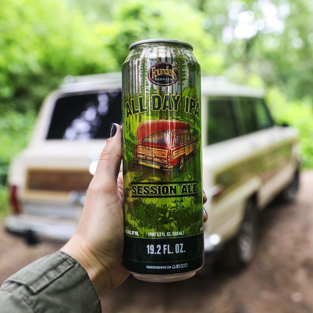 A super tall boy can of Founders All Day IPA outdoors next to a vintage car