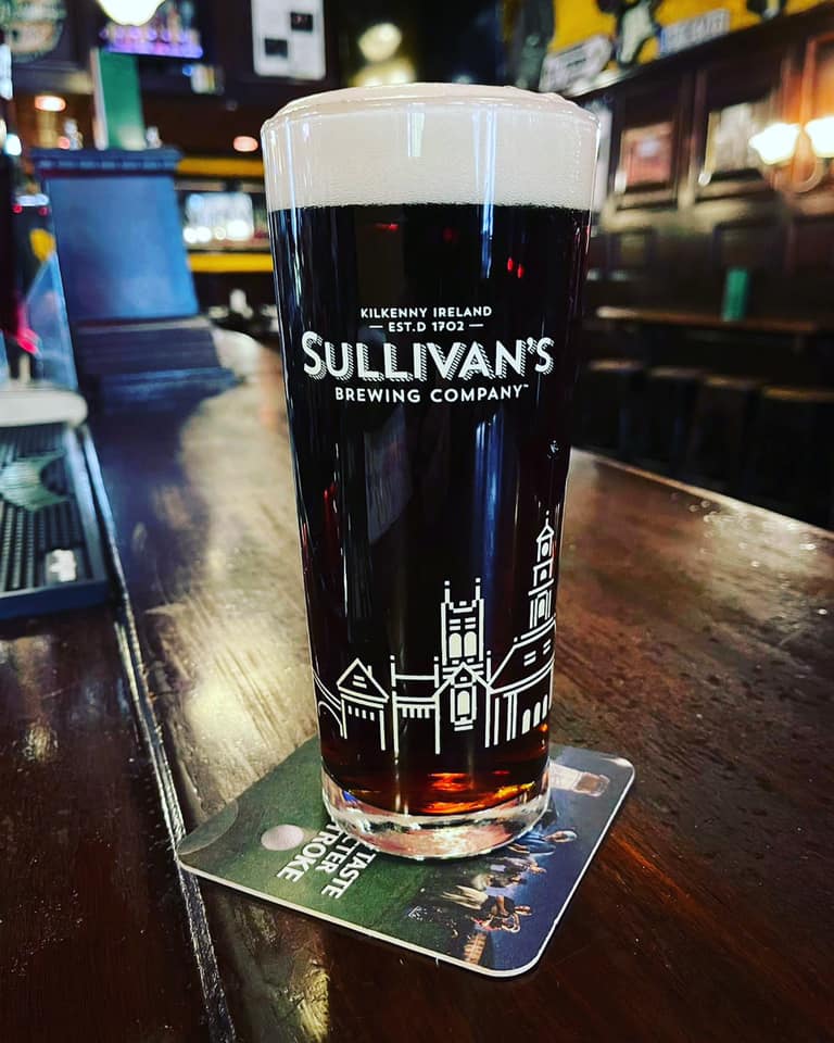 Pint of Sullivan's Black Marble stout on a wooden bar surface