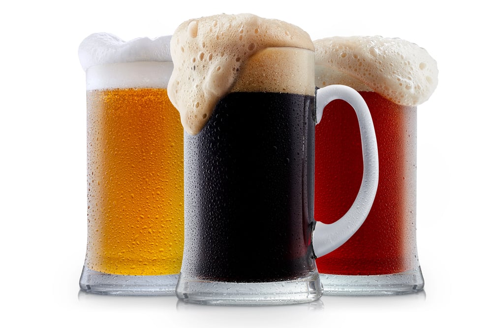 Three frosty beer mugs filled with golden lager, dark stout, and amber ale, each topped with a foamy head.