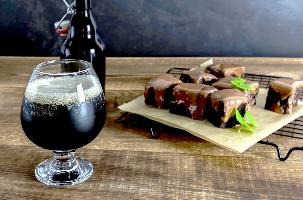 Craft beer imperial stout with sweet chocolate brownies on the wooden table.