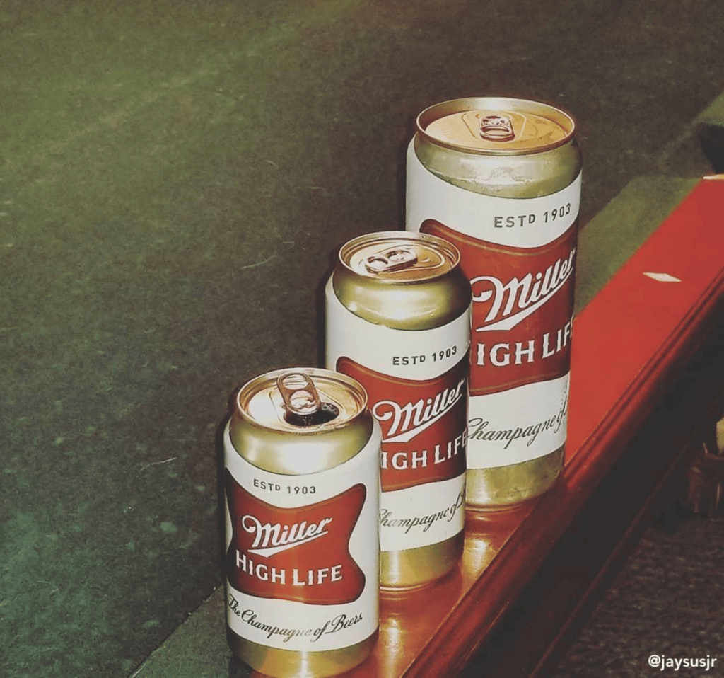 A 12-ounce Miller High Life can beside a 16-ounce tall boy and a 32-ounce "King Kan"