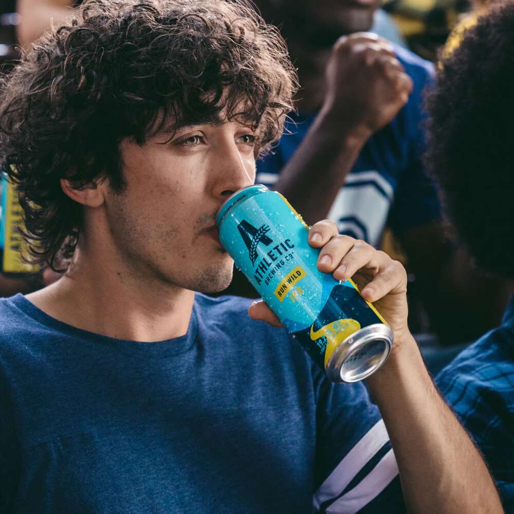 A man drinking an Athletic Brewing Run Wild IPA can.