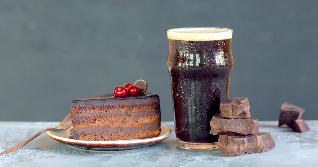 Glass of dark beer on the stone table and grey background.