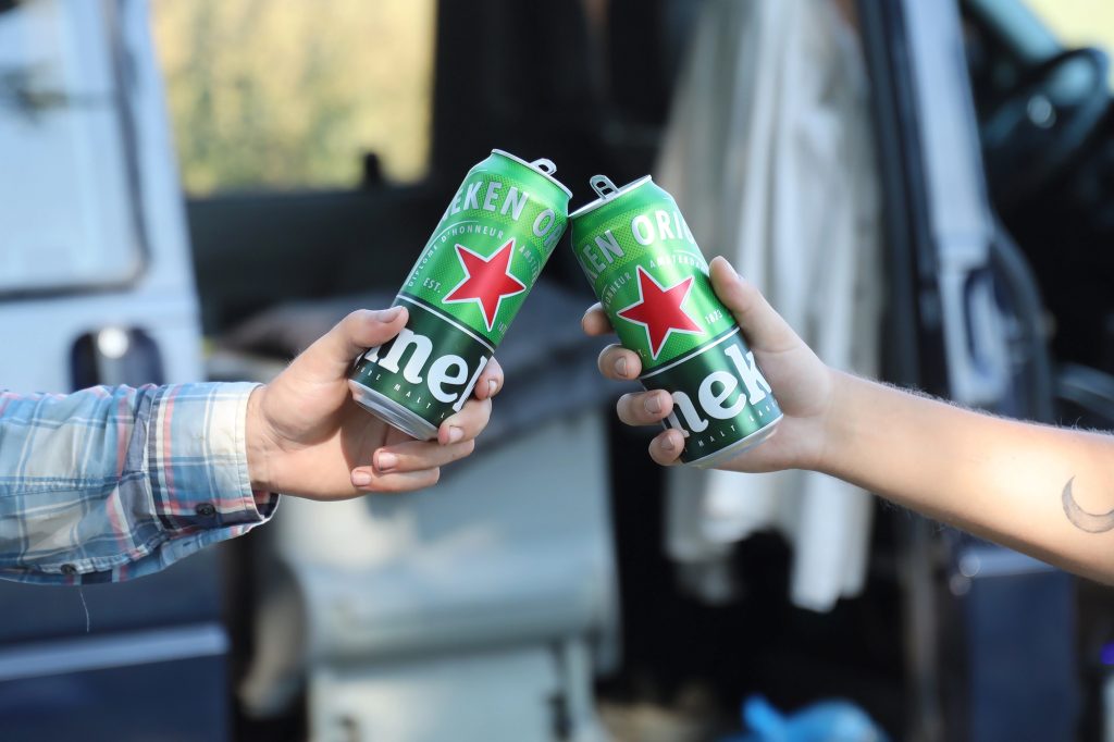 Two men toast with tall boy cans of Heineken