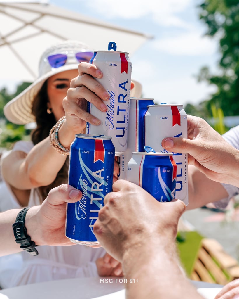 Group of people toasting with tall boy cans of Michelobe Ultra